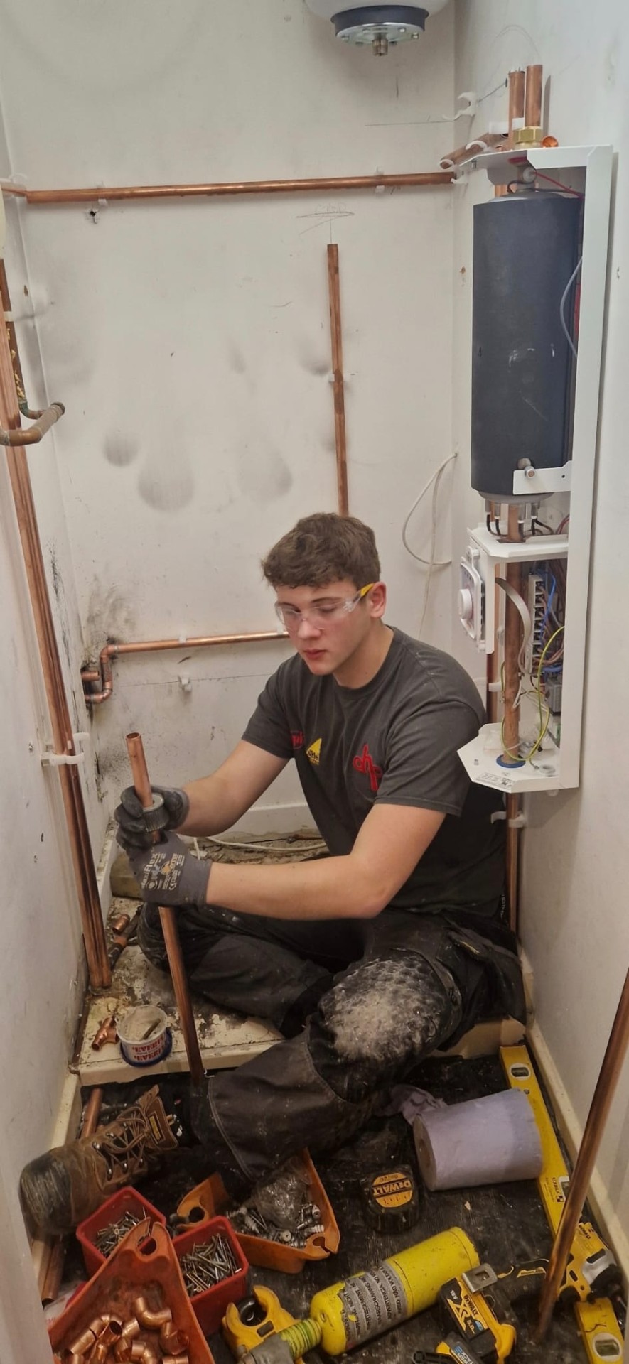 DHP London heating engineer working on copper pipework inside an airing cupboard.